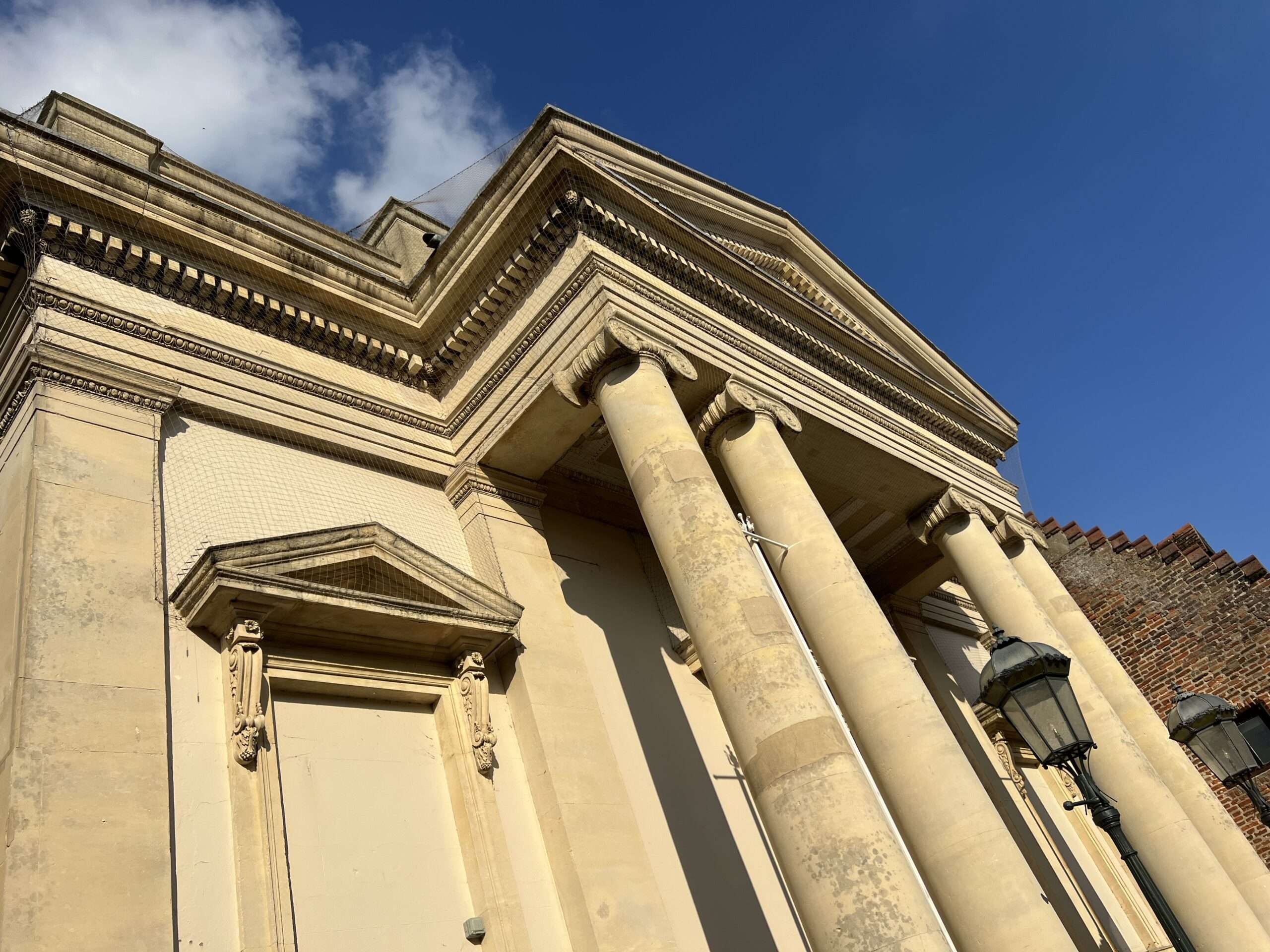 Historic Corn Hall building in Diss showing classical stone columns against a blue sky.