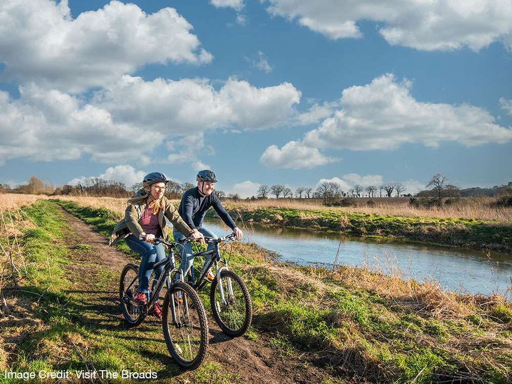 Cyclists riding hired bicycles through the Norfolk countryside on a scenic route from Bure Valley Cycle Hire.