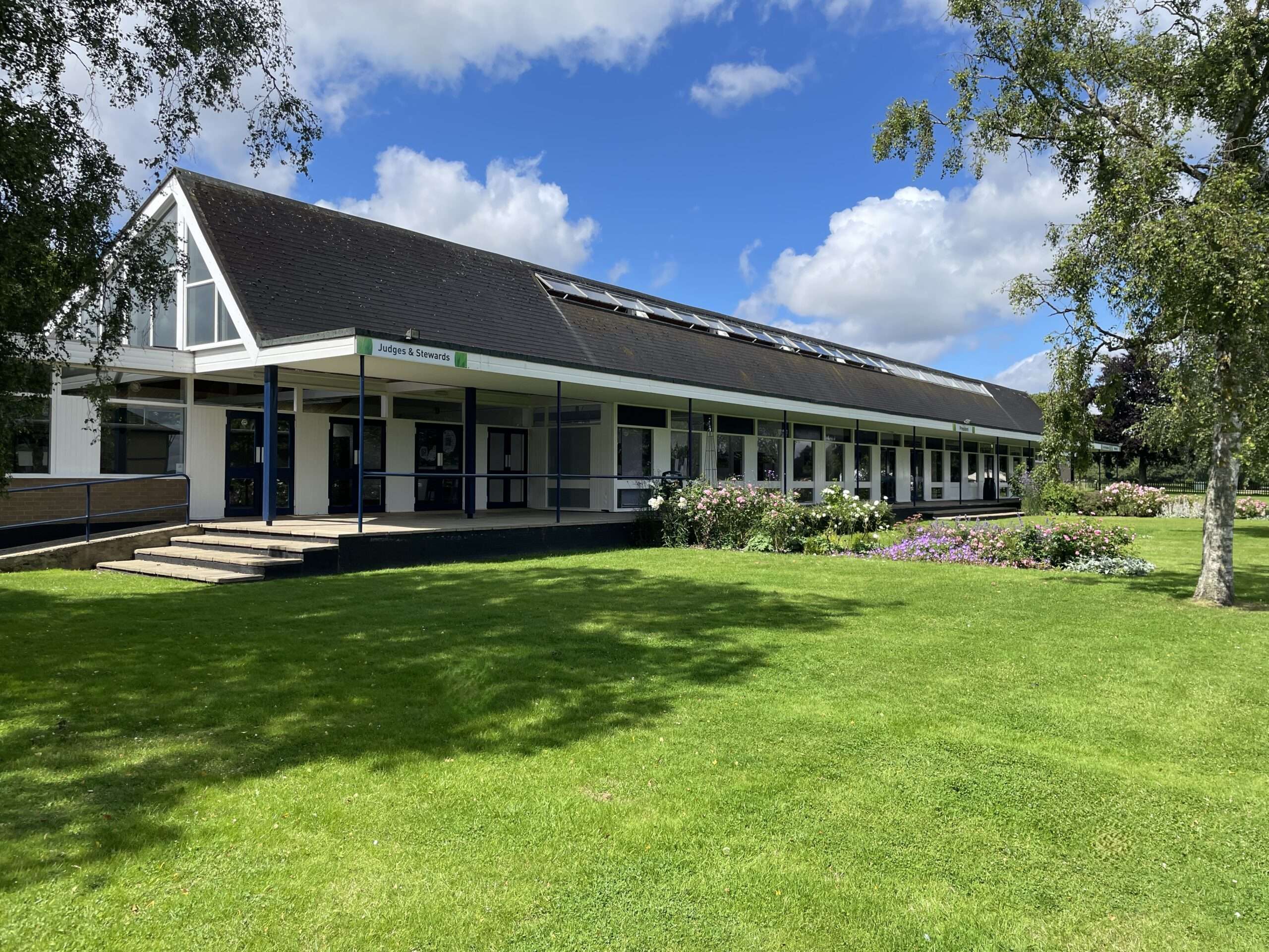 Modern pavilion building at the Norfolk Events Centre overlooking landscaped gardens and lawns on a sunny day.
