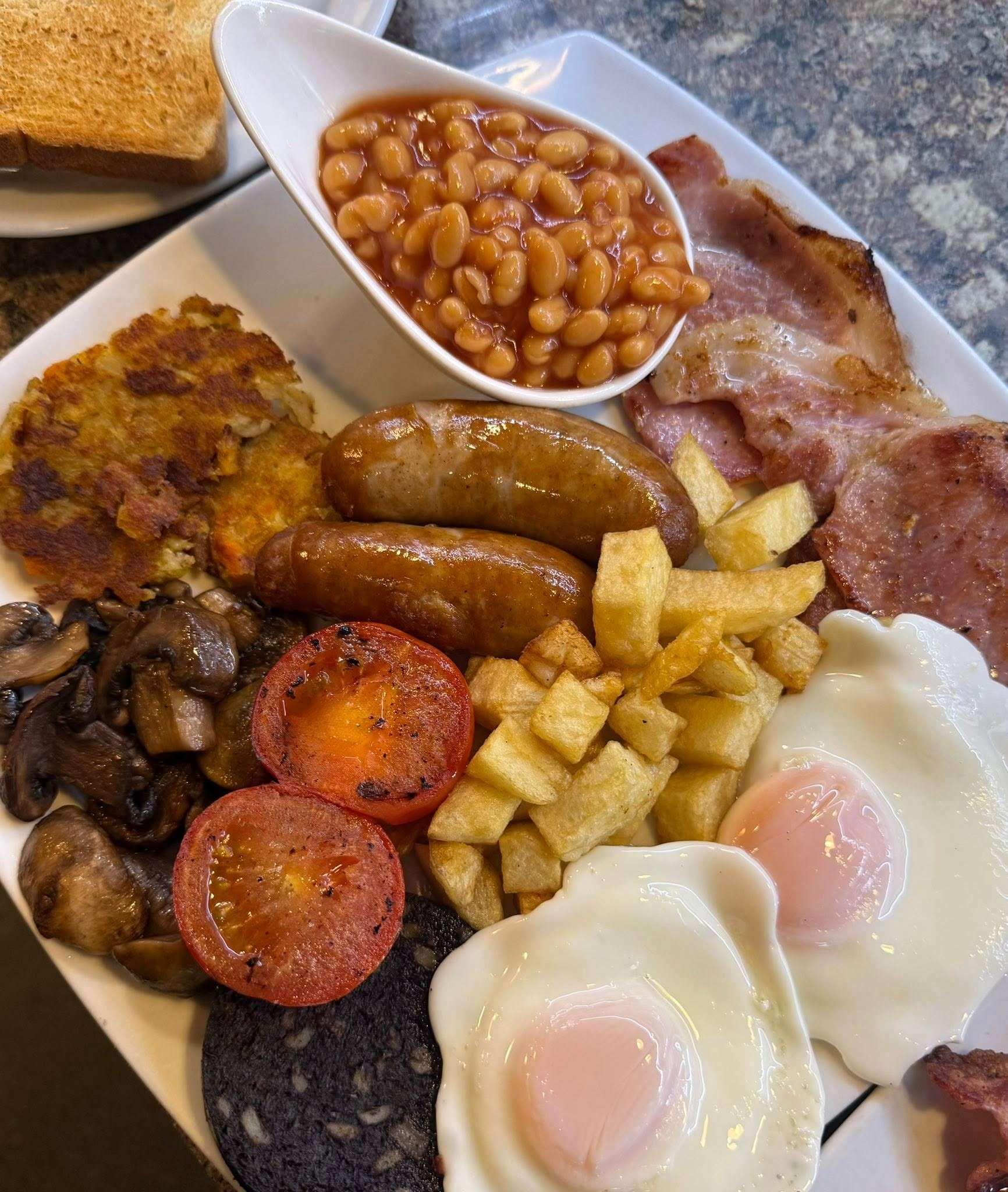 Traditional full English breakfast served at Scooters Café, featuring bacon, sausages, eggs, black pudding, beans and toast.