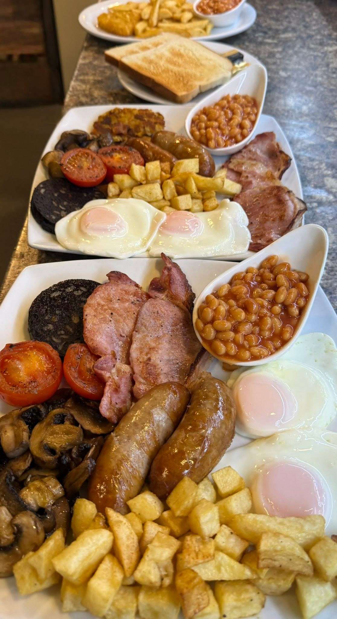 Traditional full English breakfast served at Scooters Café, featuring bacon, sausages, eggs, black pudding, beans and toast.