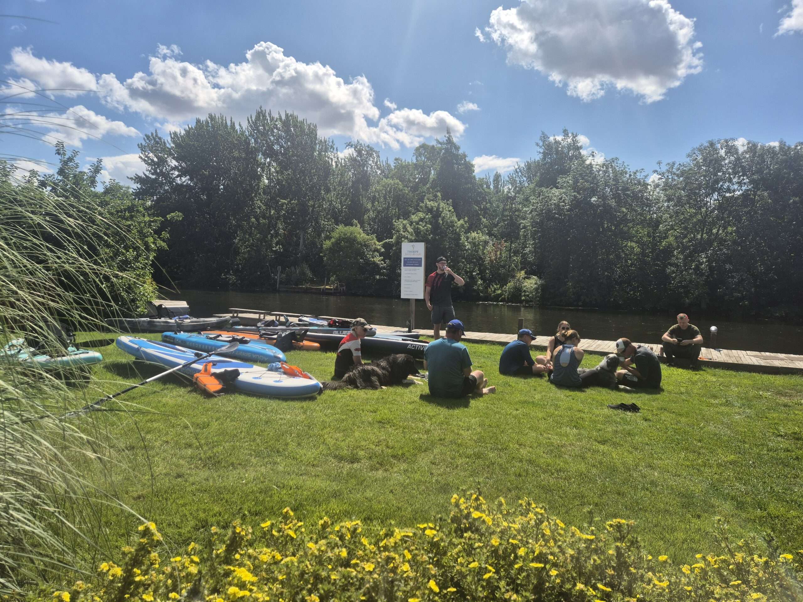 Kayaks and outdoor seating on the lawn at Thorpe Ferry Café beside the River Yare