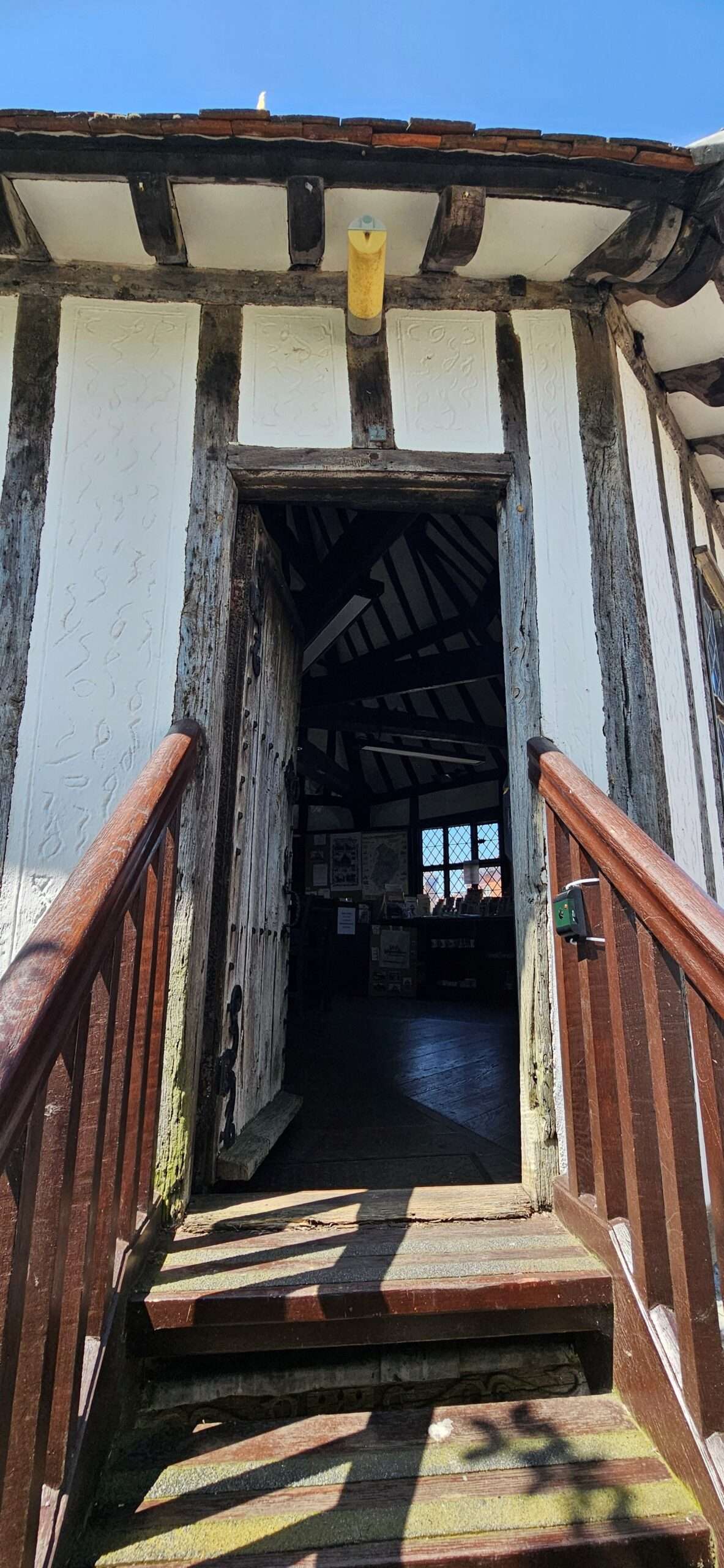 Wooden staircase leading to an upper floor within a historic timber-framed building, featuring exposed beams and traditional architecture.