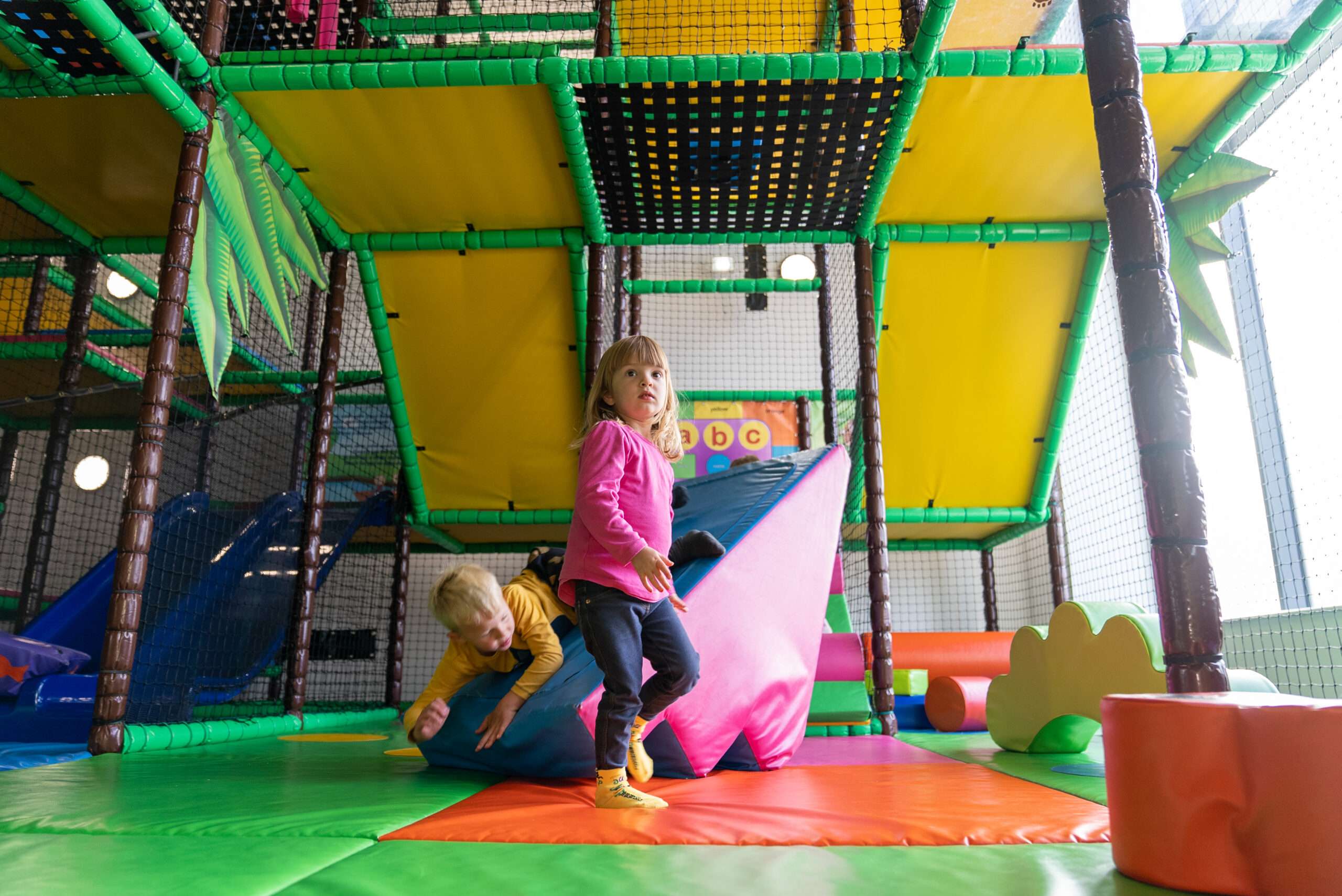 Child climbing and exploring the colourful multi-level soft play frame at Bananas Soft Play in Norfolk.